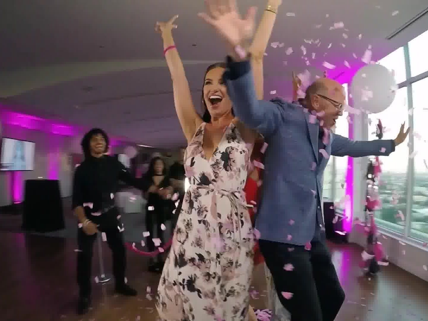 Guests celebrating in a shower of confetti beside a 360 photo booth