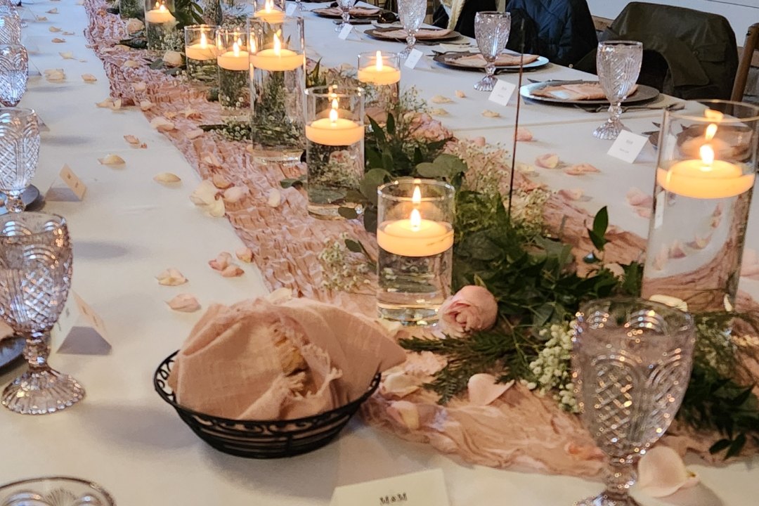 Long reception table styled with blush runners, floating candles, greenery and place cards