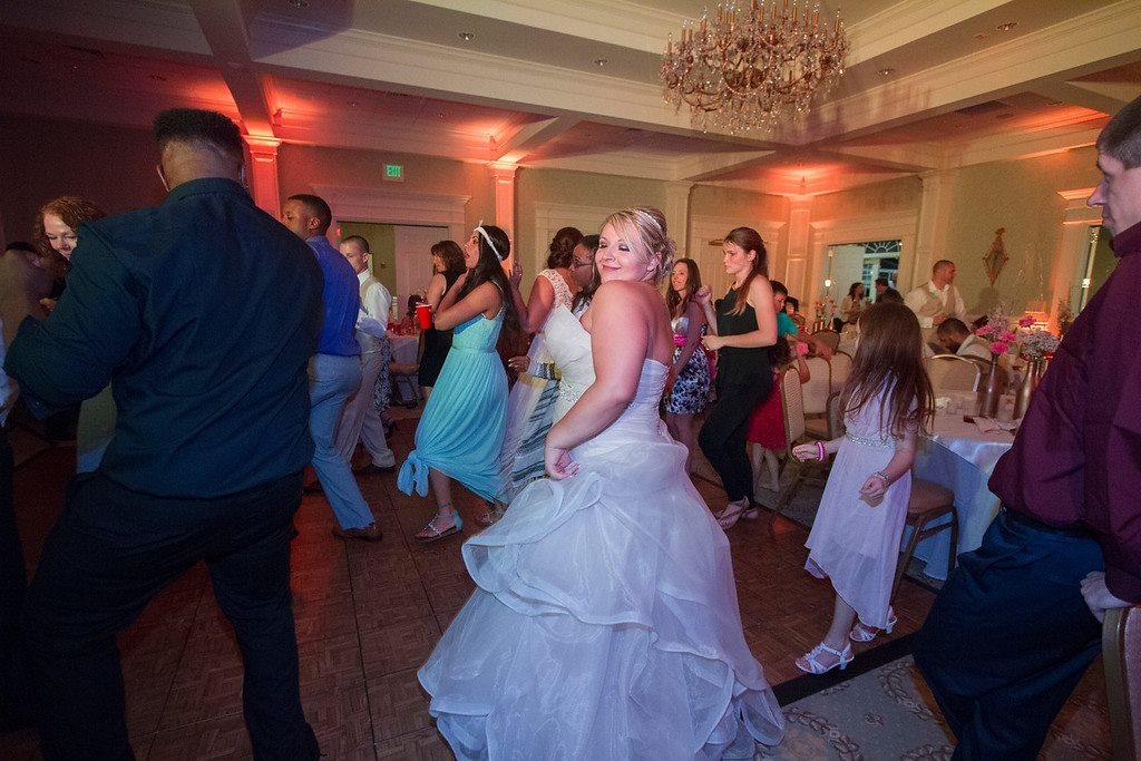 Bride dancing with her guests in a ballroom washed in amber uplighting