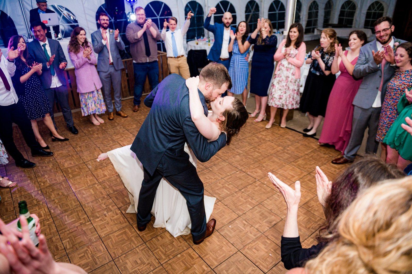 Couple dipping into a kiss as guests applaud around the dance floor