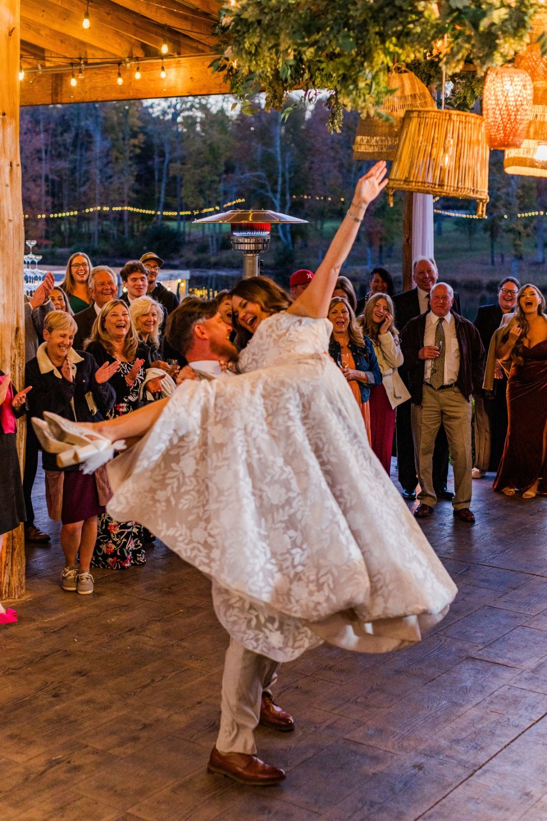 Groom lifting and spinning the bride at an open-air reception
