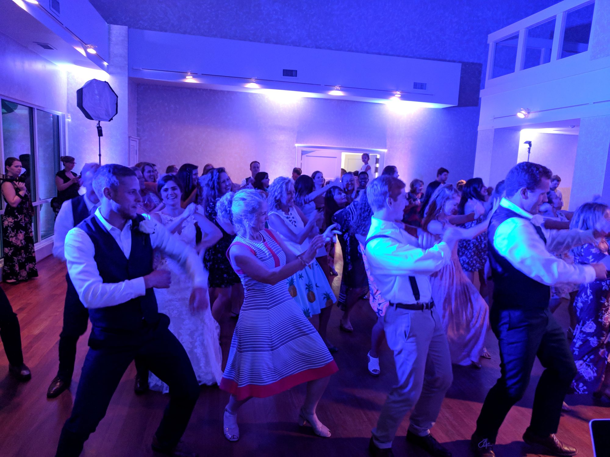 Wedding guests filling a dance floor lit in deep blue and gold