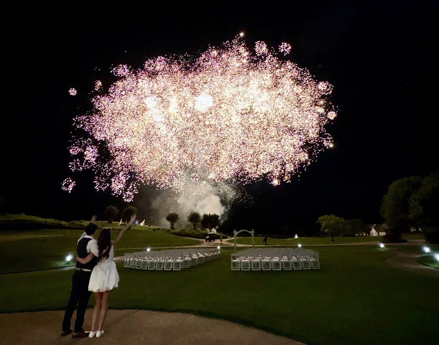 Aerial shells bursting above a lawn at night