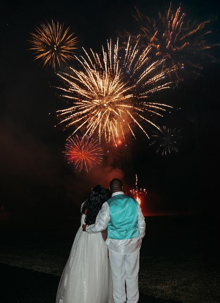 Couple watching a fireworks display from the lawn of their venue
