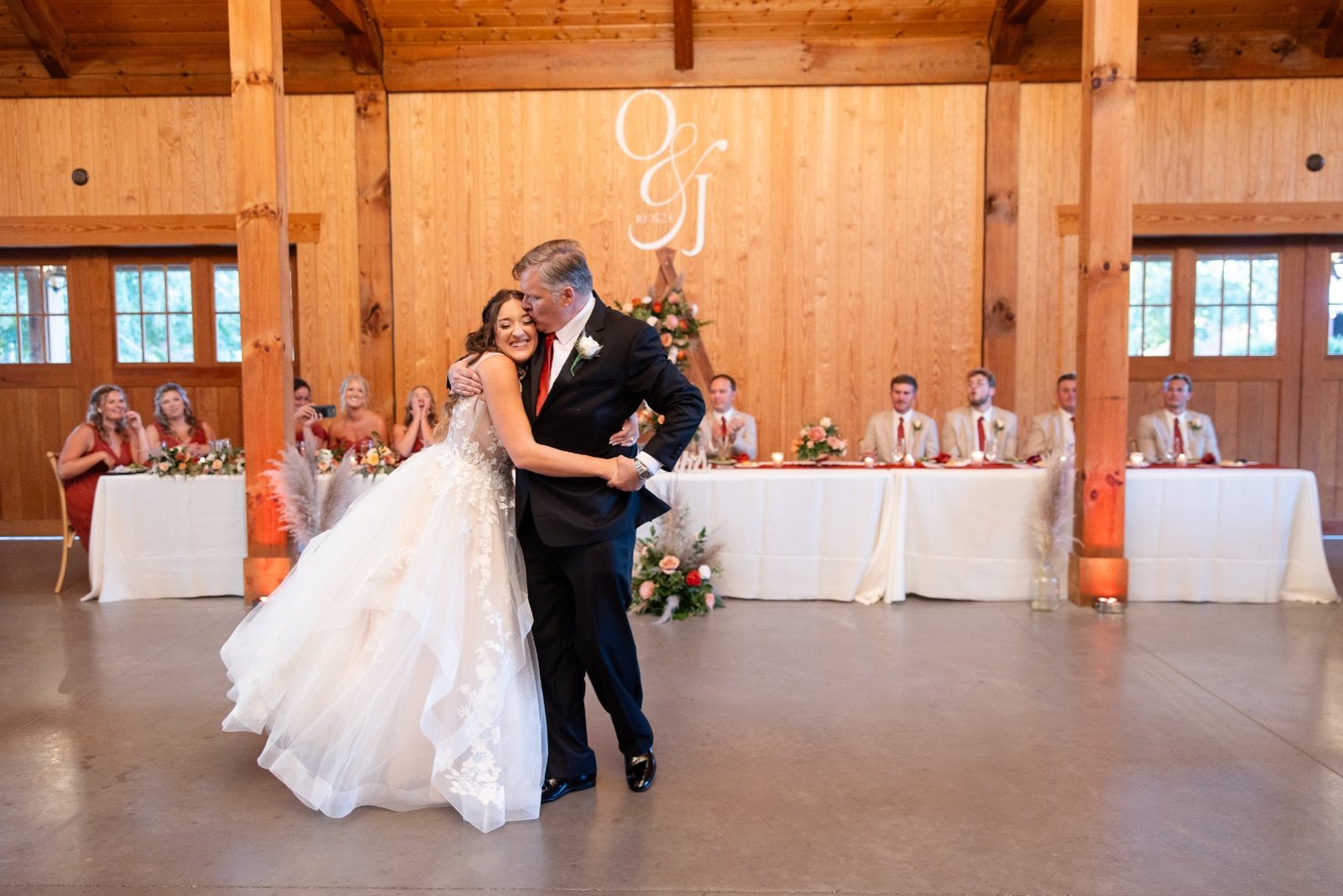 Father-daughter dance in a timber barn reception with a projected monogram