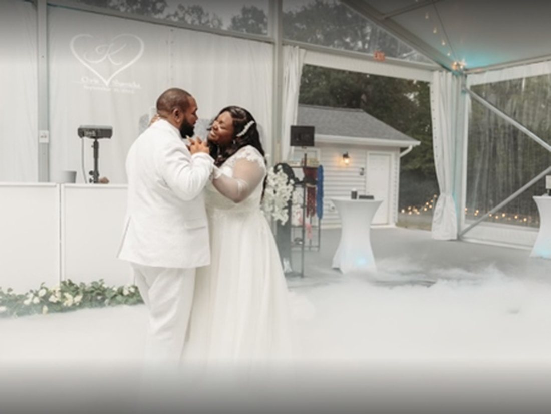 Couple sharing a first dance on a cloud of low-lying fog under a clear tent